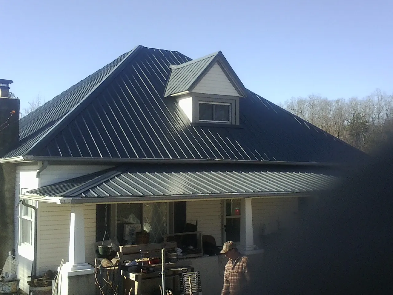 Dark blue standing seam metal roof with a dormer above a front porch in Horseshoe Bay