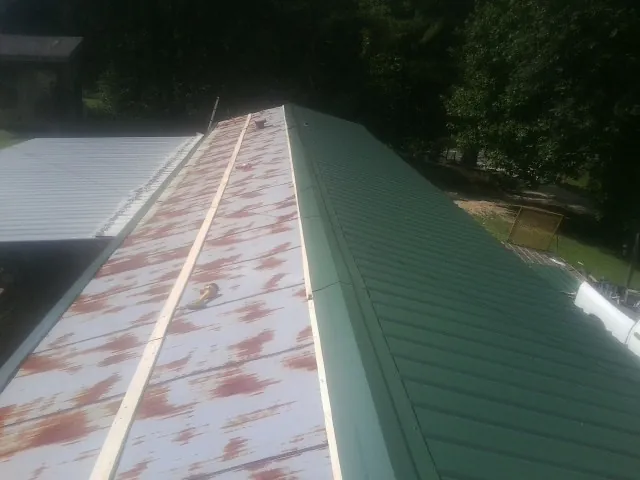 Old rusted panels beside newly installed green metal roofing — Wind Damage Roof Repair by Roofing Brothers in Horseshoe Bay