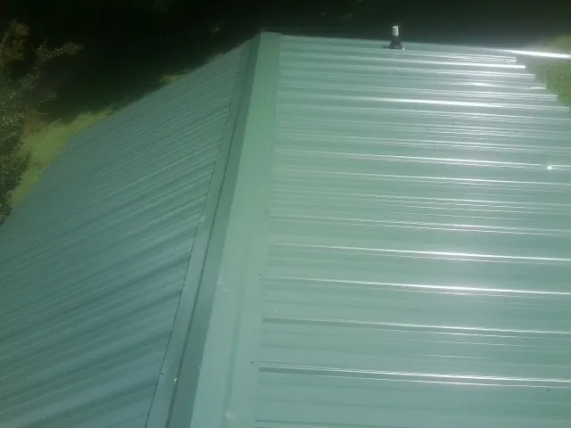 New green metal panels meeting at the ridge of a roof — Flat Roof Repair work by our crew in Horseshoe Bay