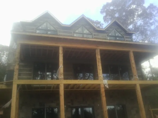 Dormers and porch framing on a large log home under construction — Roof Coating work by our crew in Horseshoe Bay