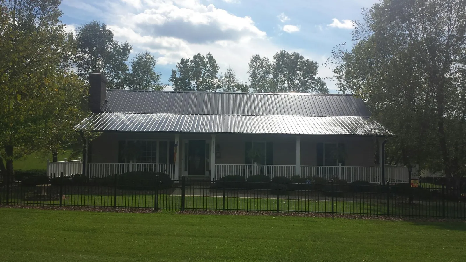 Gray metal roof on a brick ranch with a full width front porch — Gutter Guard Installation work by our crew in Horseshoe Bay