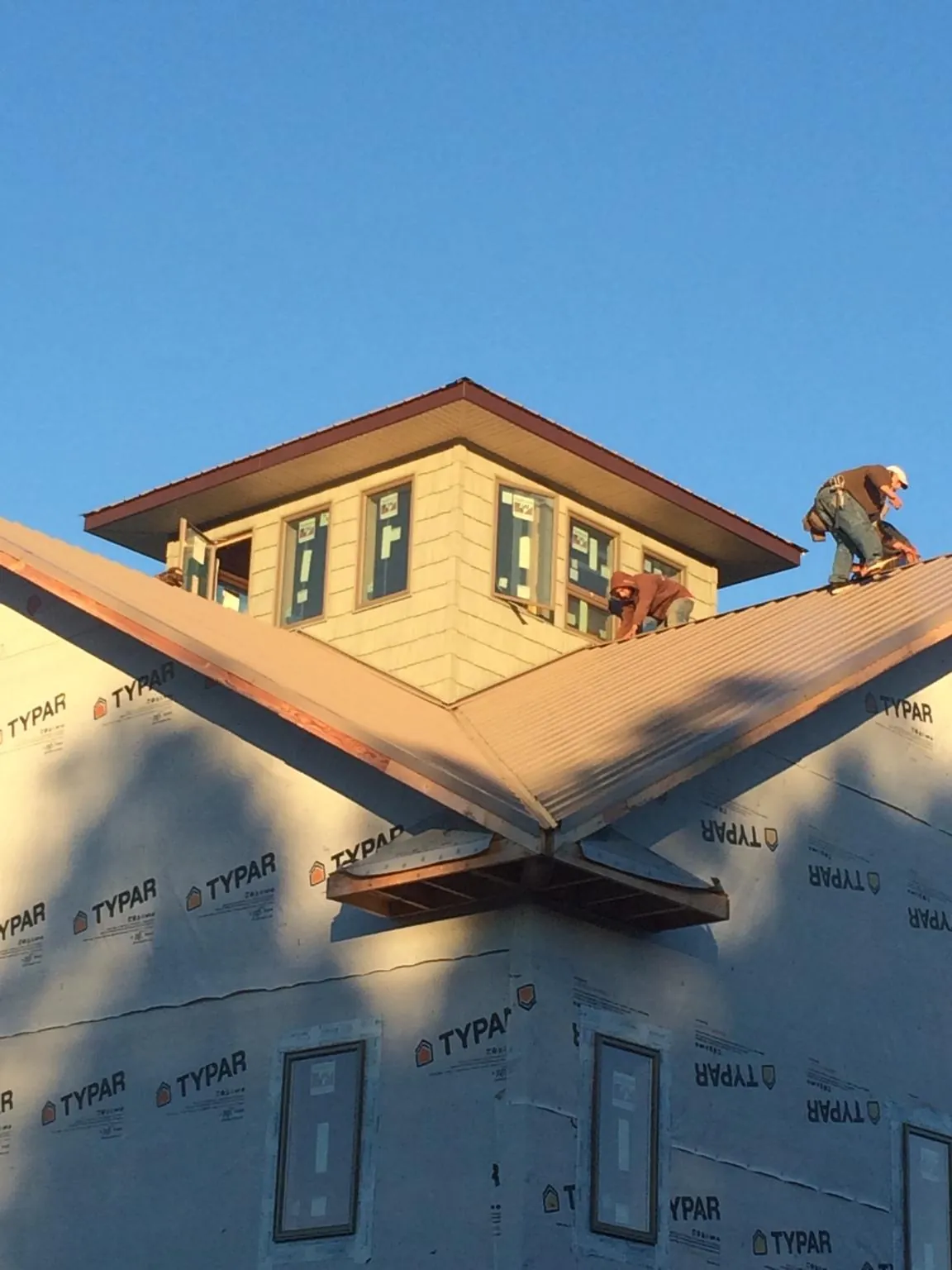 Roofers working around a rooftop cupola on a new metal roof at sunset — Roof Waterproofing in Horseshoe Bay by Roofing Brothers